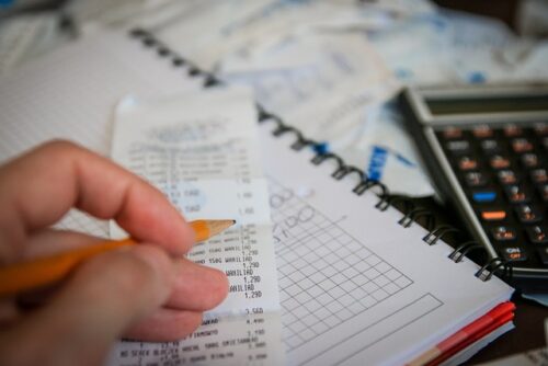 person writing next to calculator