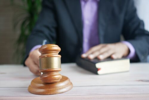 man holding gavel with hand on book