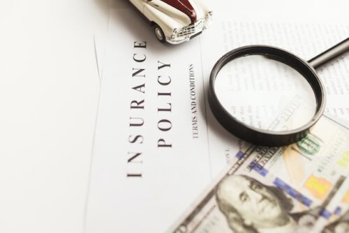 insurance policy paper, magnifying glass, and money