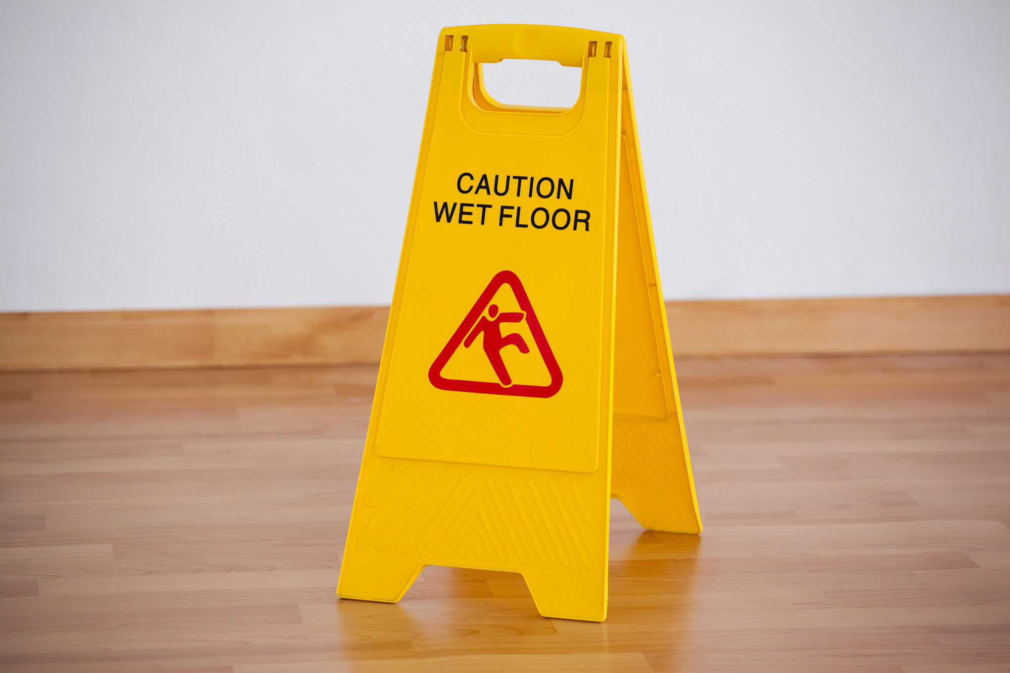 Caution wet floor sign on a hardwood floor; Sacramento Slip & Fall Lawyer concept image