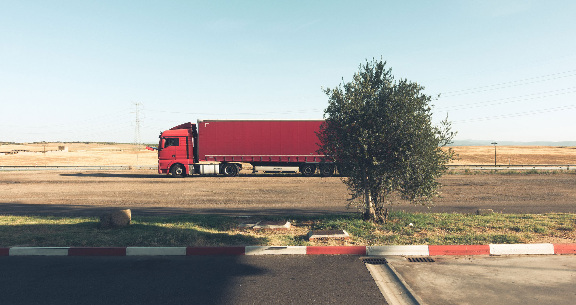 An 18 wheeler truck hauling a freight trailer down a rural road on a sunny day in Sacramento county; Sacramento Truck Accident Lawyer concept image