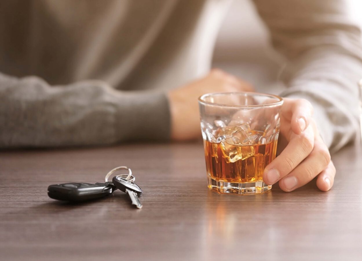 person with whiskey at a table next to car keys